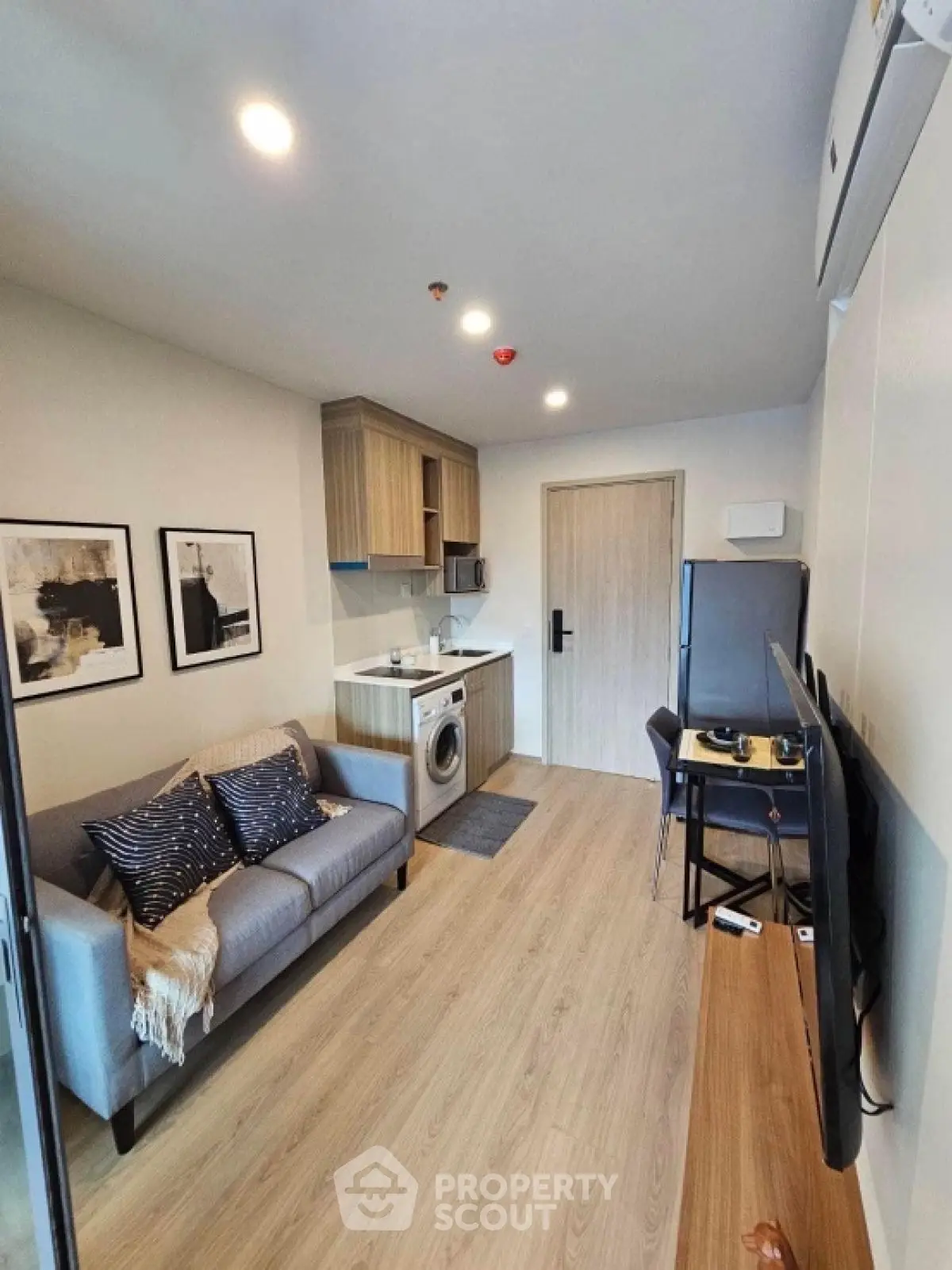 Modern compact living room with kitchen and washing machine in stylish apartment