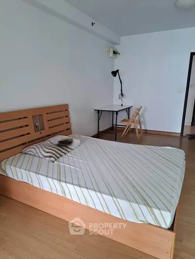 Spacious bedroom with wooden bed frame and study desk, ideal for comfort and productivity.