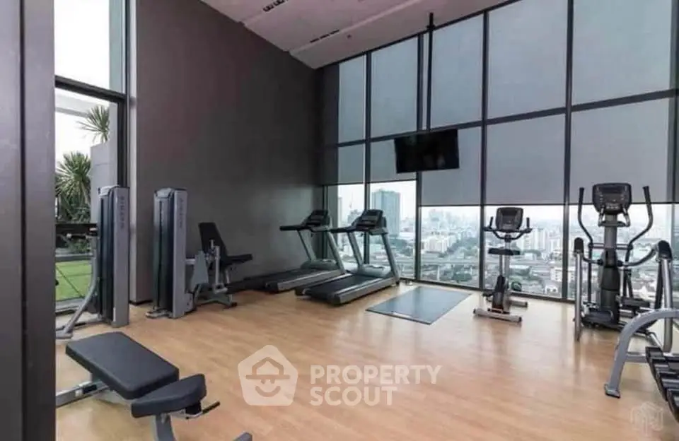 Modern gym with city view, featuring state-of-the-art equipment and floor-to-ceiling windows.