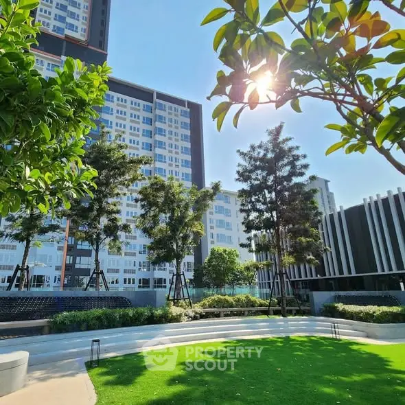Modern residential building with lush green garden and trees under clear blue sky.
