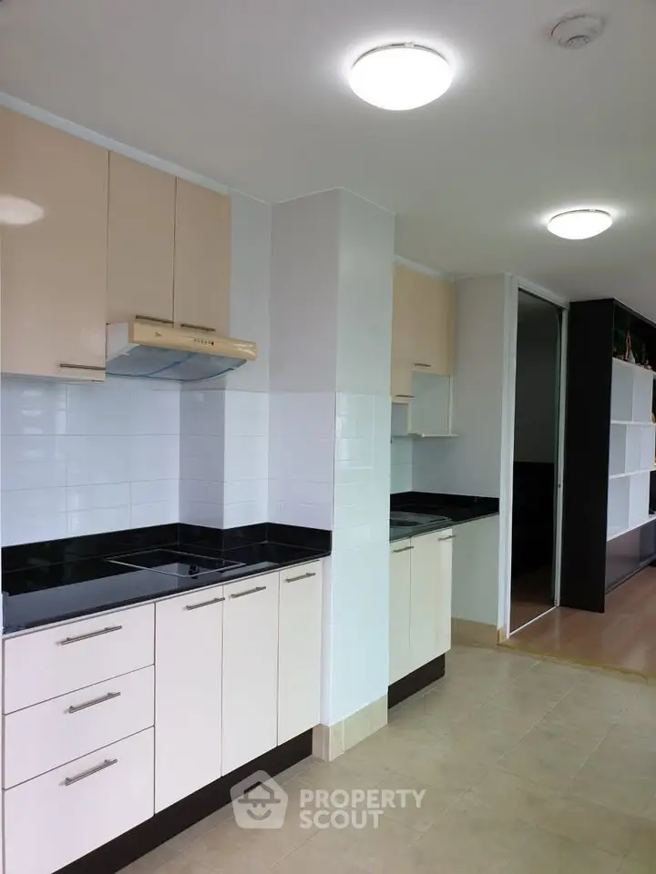 Modern kitchen with sleek cabinets and black countertops in a bright apartment.