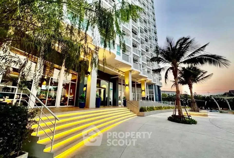 Stunning modern building entrance with illuminated steps and lush palm trees at sunset.