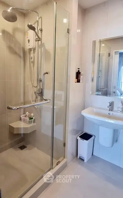 Modern bathroom with glass shower enclosure and sleek fixtures in a contemporary apartment.