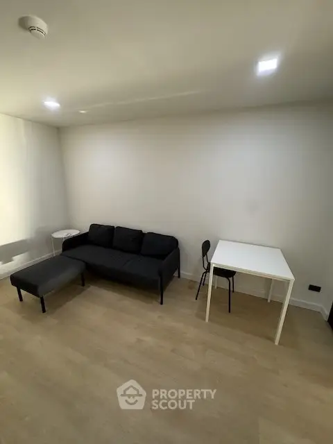 Modern minimalist living room with black sofa and white table, perfect for cozy urban living.