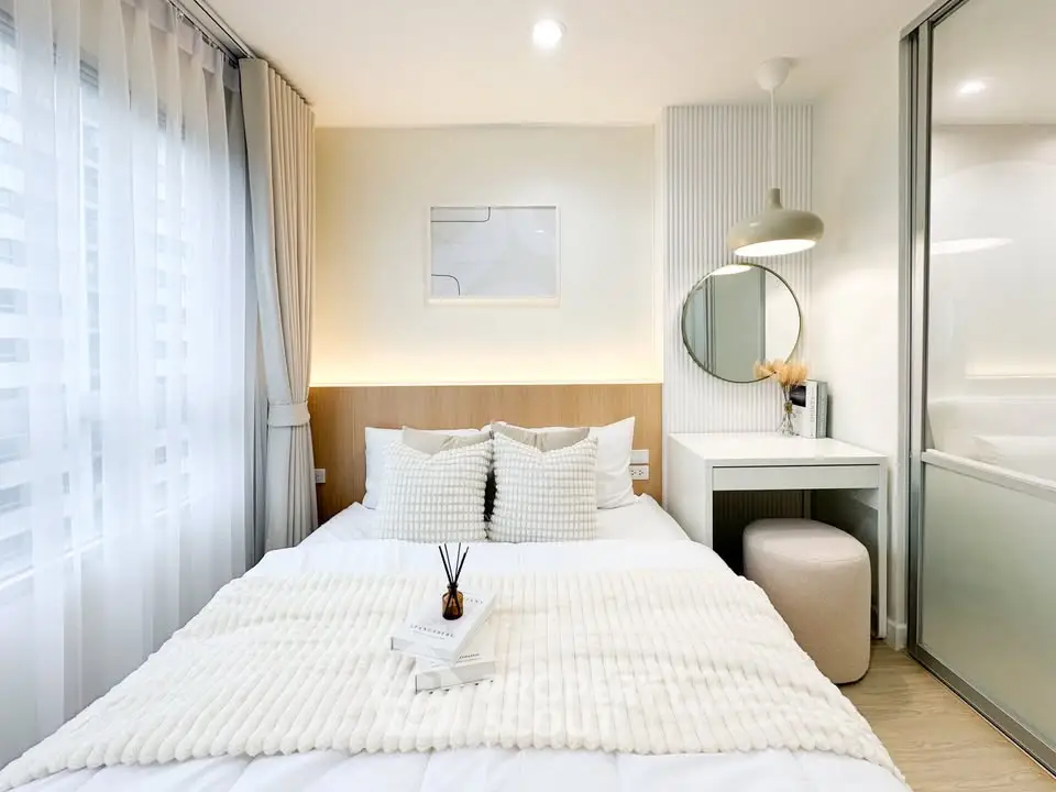 Modern bedroom with cozy decor, featuring a plush bed, elegant lighting, and a stylish vanity area.