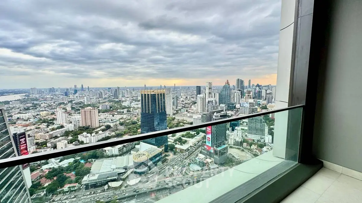 Stunning cityscape view from high-rise balcony with glass railing.