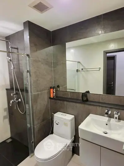Modern bathroom with sleek fixtures and contemporary design, featuring a glass shower and stylish vanity.