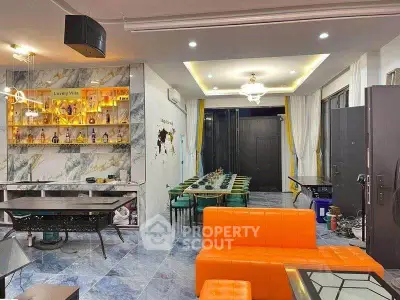 Luxurious modern living room with vibrant orange sofa and elegant dining area in a stylish villa.