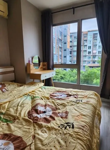 Cozy bedroom with large window and city view, featuring a stylish vanity and vibrant bedding.