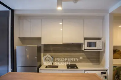Modern kitchen with sleek cabinetry, stainless steel fridge, and built-in microwave.