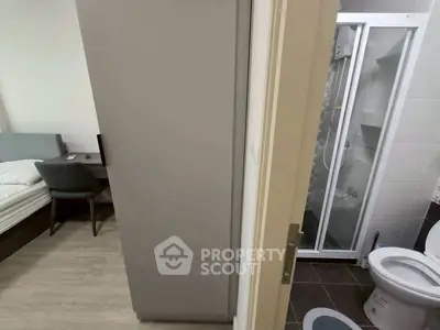 Compact apartment with bedroom and bathroom, featuring modern shower and cozy workspace.