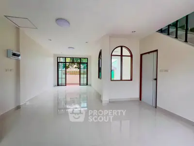Spacious modern living room with large windows and glossy floors in a bright, open layout.