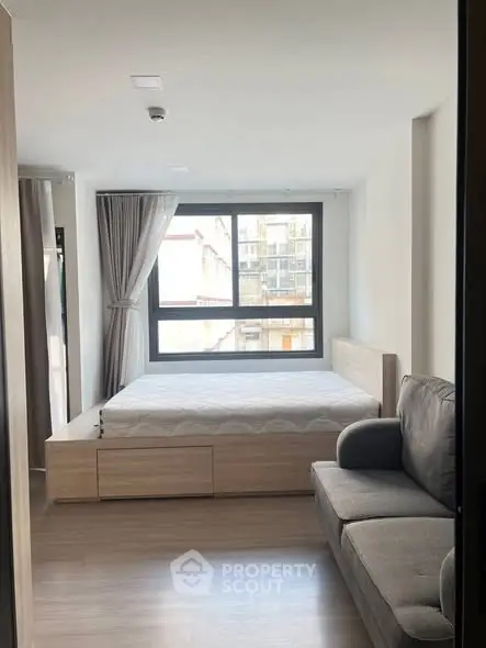 Modern bedroom with large window and cozy sofa in a stylish apartment.