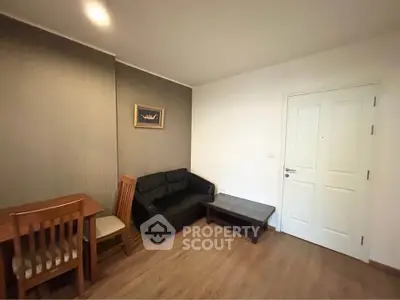 Cozy living room with wooden flooring, sofa, and dining table in modern apartment.
