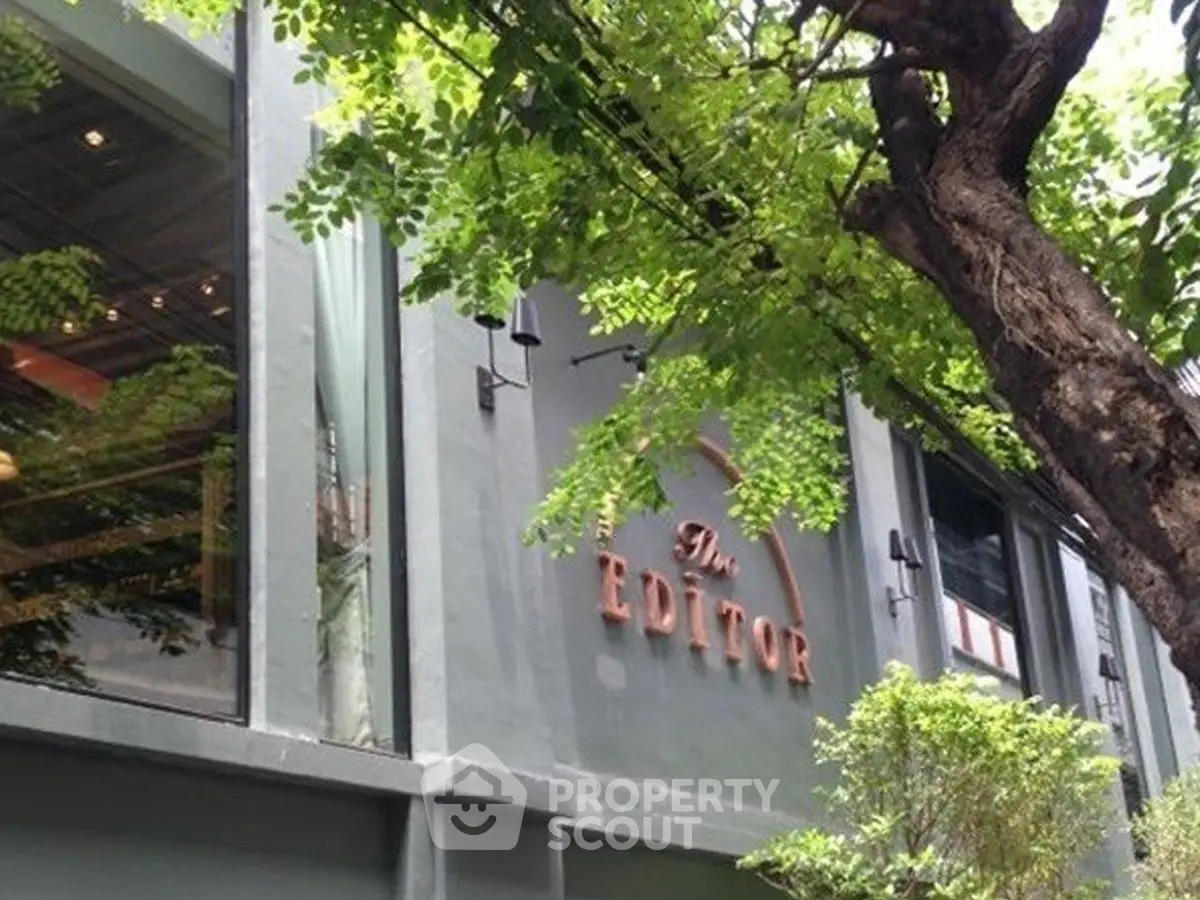 Modern building exterior with lush greenery and large windows, showcasing urban architectural elegance.