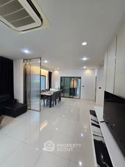 Spacious modern living room with sleek design and dining area, featuring glossy tile flooring and elegant furnishings.