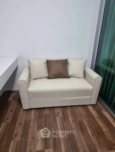 Cozy small living room with modern beige sofa and wooden flooring