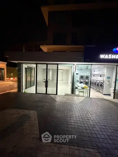 Modern laundromat exterior with glass doors and bright lighting, open 24 hours for convenience.