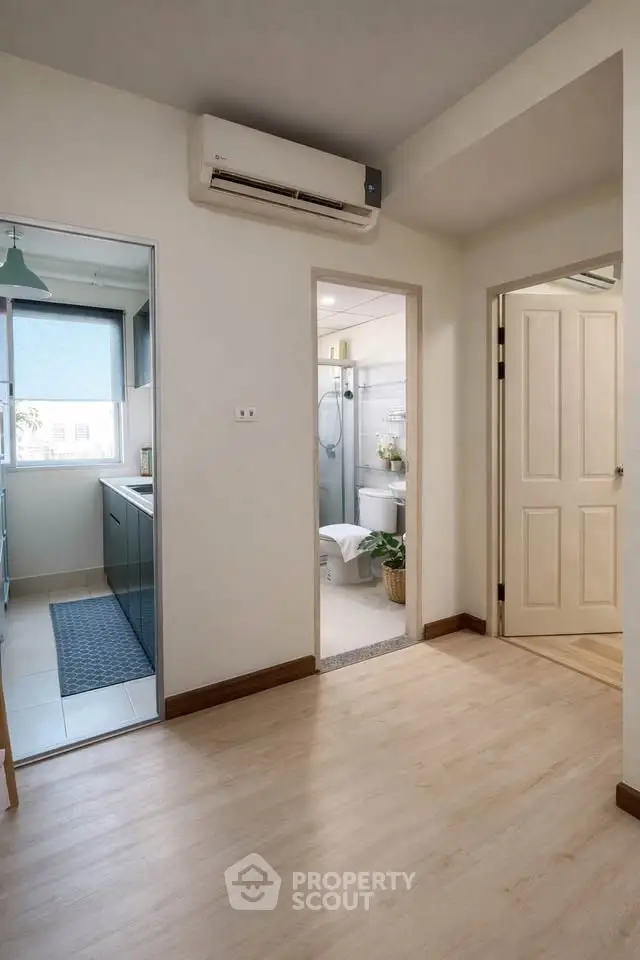 Modern apartment hallway with view into kitchen and bathroom, featuring sleek design and natural light.