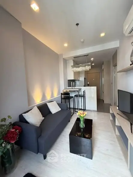 Modern living room with open kitchen, stylish decor, and cozy seating in a contemporary apartment.