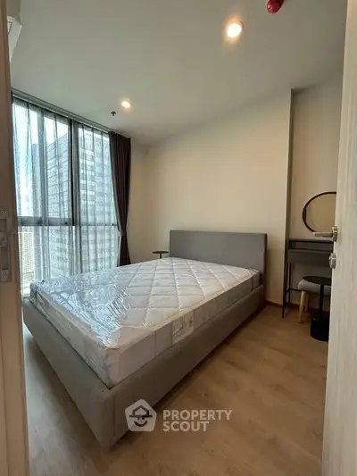 Modern bedroom with large window and stylish furniture in high-rise apartment.