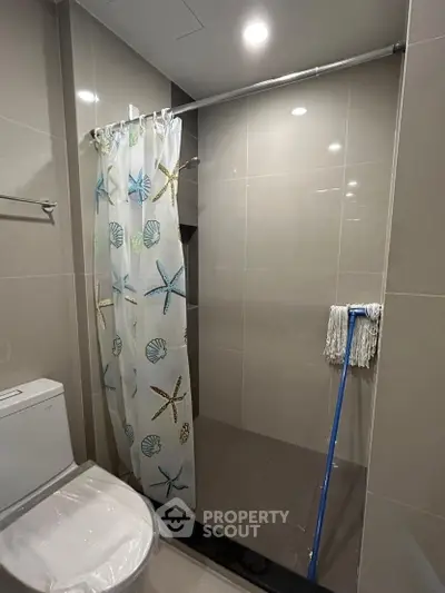 Modern bathroom with shower curtain and toilet in sleek design.