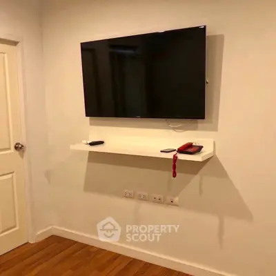 Modern living room with wall-mounted TV and sleek wooden flooring