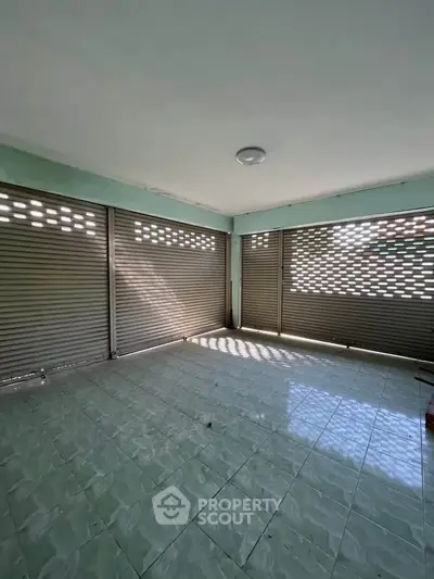 Spacious tiled room with large shuttered windows offering ample natural light.