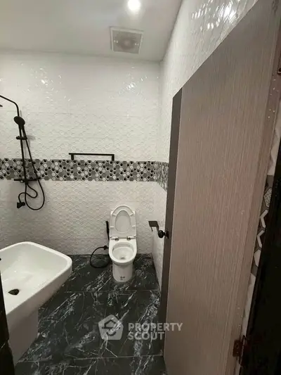 Modern bathroom with sleek black and white design, featuring a stylish sink and toilet.