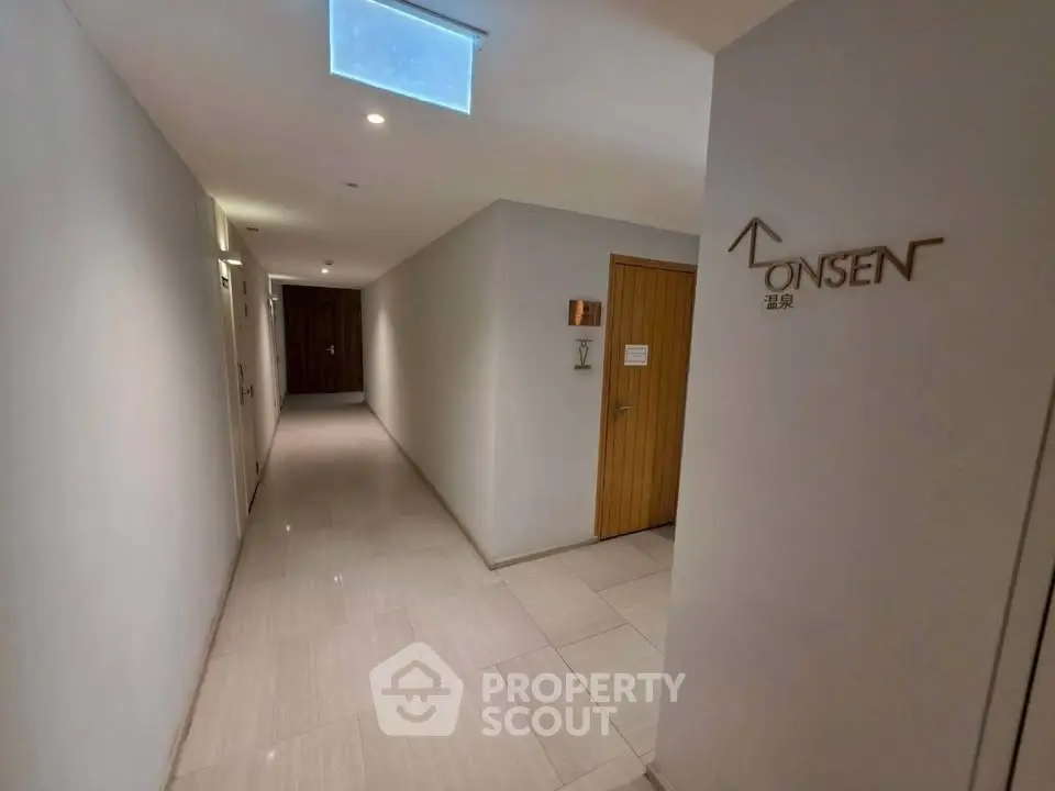 Modern hallway leading to onsen spa with sleek design and ambient lighting.