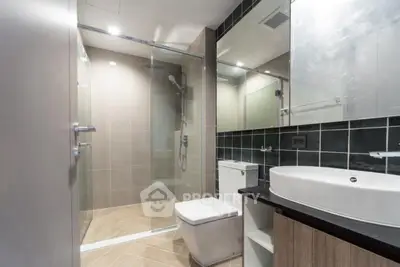 Modern bathroom with glass shower and sleek fixtures in contemporary apartment.