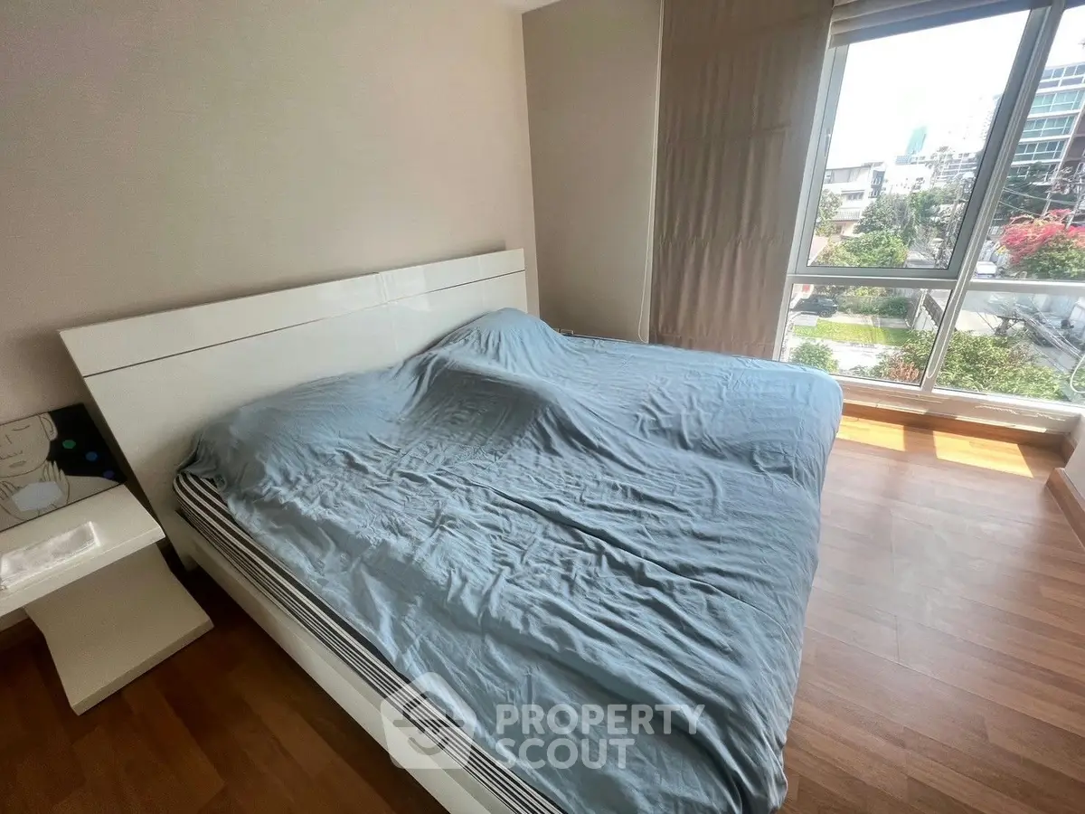 Spacious bedroom with large window offering city views and natural light.