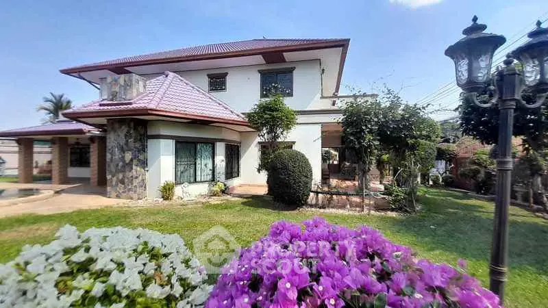Charming two-story house with lush garden and vibrant flowers, perfect for family living.
