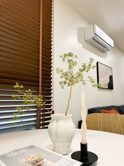Modern interior with stylish decor, featuring a white vase, twisted candle, and air conditioning unit.