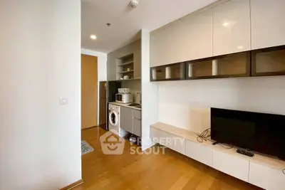 Modern apartment interior with sleek cabinetry and hardwood floors, featuring a compact kitchen and living area.
