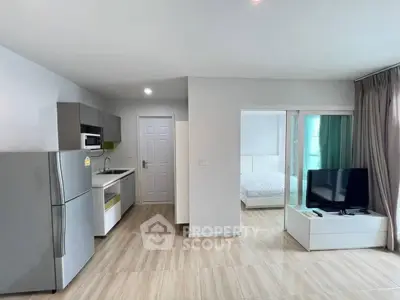Modern open-plan living room with kitchen and bedroom view, featuring sleek appliances and stylish decor.