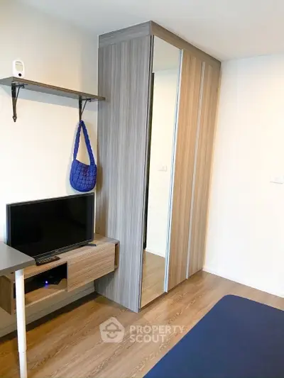 Modern bedroom with sleek wooden wardrobe and compact TV setup