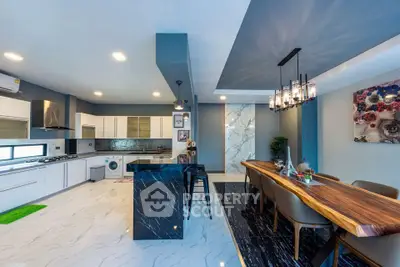 Luxurious modern kitchen with open layout and elegant dining area, featuring sleek black and white design.
