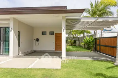 Modern home exterior with carport and lush garden, showcasing sleek design and spacious outdoor area.