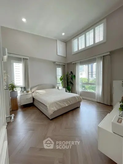 Spacious bedroom with large windows and modern decor, offering abundant natural light and a serene atmosphere.