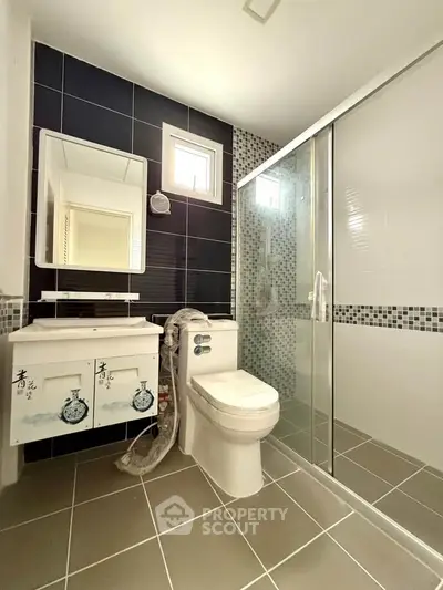 Modern bathroom with sleek design, featuring glass shower and stylish vanity.