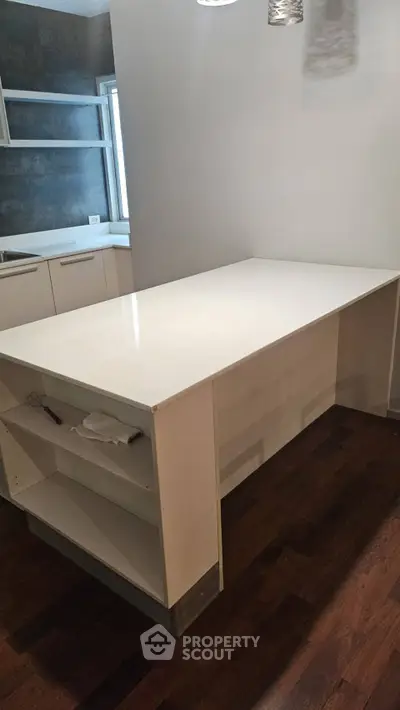 Modern kitchen with sleek white island and dark wood flooring, perfect for culinary enthusiasts.