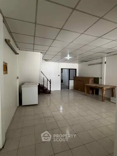Spacious basement area with tiled flooring and staircase, ideal for storage or renovation.