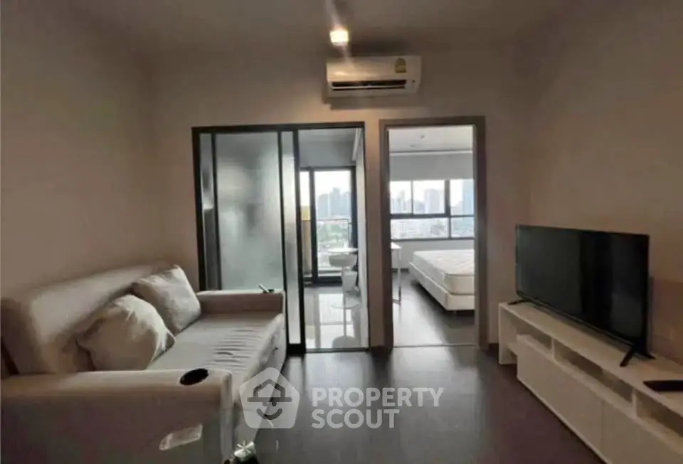 Modern apartment interior with cozy living room and bedroom view, featuring sleek furniture and cityscape backdrop.