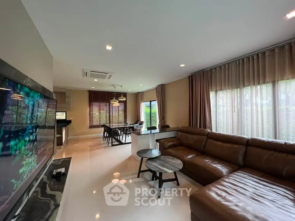 Spacious modern living room with leather sofa and large windows in a stylish home.