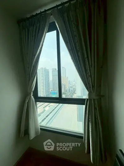 Cozy room with large window offering stunning cityscape view, perfect for urban living enthusiasts.