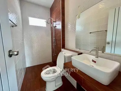 Modern bathroom with sleek fixtures and wood accents, featuring a spacious shower and stylish sink.