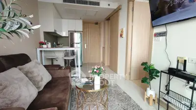 Modern living room with open kitchen, stylish decor, and cozy seating in a contemporary apartment.