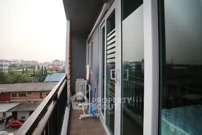 Spacious balcony with city view in modern apartment, featuring sliding glass doors and ample outdoor space.