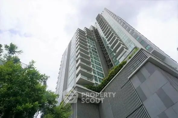 Modern high-rise building with lush greenery and sleek architectural design.